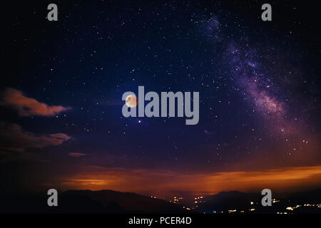 Red moon during the eclipse and in the background the milky way. Composition of multiple images exhibited differently. Stock Photo