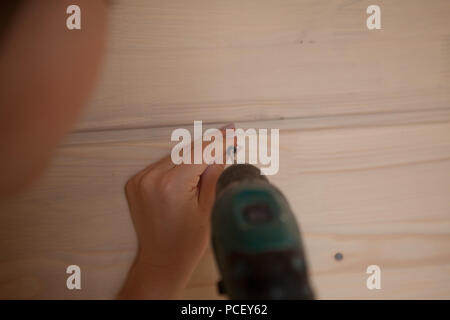 Close-up the woman holding the screw and the electric screw-driver Stock Photo