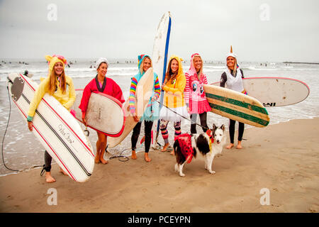 Wearing fanciful costumes including a rabbit and a unicorn and hefting their surfboards, six women and a dog in a skirt line up at a Halloween costumed surfing event in Huntington Beach, CA.  (Photo by Spencer Grant) Stock Photo