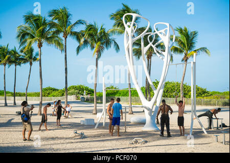 MIAMI - CIRCA JUNE, 2018: Muscular young men work out in the outdoor gym known as Muscle Beach in Lummus Park.