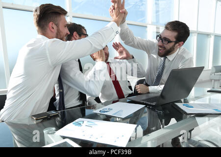 employees give each other a high five sitting at the Desk Stock Photo ...