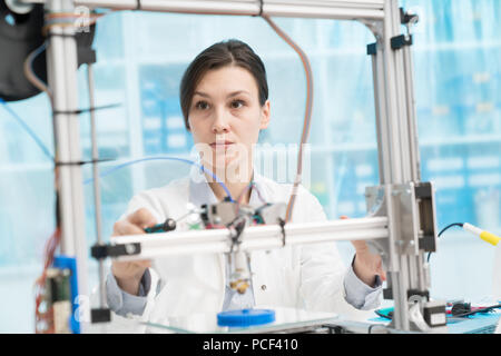 female student or laboratory assistant in the automation laboratory is debugging the work of the 3d printer. 3d printer is a device for modeling objec Stock Photo