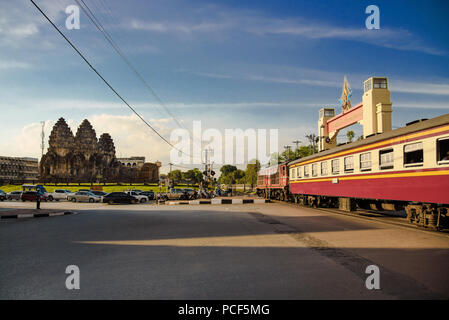 The train crossing the road at the 13th century Phra Prang Sam You temple in Lopburi Province, Thailand. Stock Photo