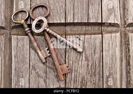 Vintage keys on old wooden background. Close-up. Three old, rustic keys on the table. Stock Photo