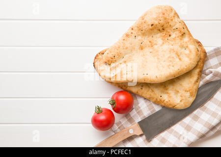 Indian naan bread and tomatoes on white kitchen table. Stock Photo
