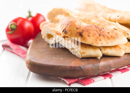 Indian naan bread and tomatoes on white kitchen table. Stock Photo