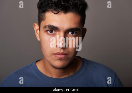 Studio portrait of a 19 years old young man, in a blue t-shirt, looking to the camera Stock Photo