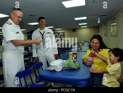 Rear Adm. C. Forrest Faison III, commander of Navy Medicine West, gives a thumbs-up to a boy and his parents in the mess decks aboard the Military Sealift Command hospital ship USNS Mercy (T-AH 19). Nearly 500 medical and support staff from Navy Medicine West are deployed aboard Mercy supporting Pacific Partnership 2012. Pacific Partnership is an annual U.S. Pacific Fleet humanitarian and civic action exercise designed to work with and through host nations to build partnerships and a collective ability to respond to natural disasters. Stock Photo