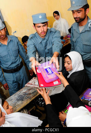 KABUL, Afghanistan - Afghan National Civil Order Police patrolmen hand out school supplies to students in a Kabul classroom. ANCOP Command Sgt. Maj. Abdul Wihad spearheads the donation of school supplies which takes place once a month Stock Photo
