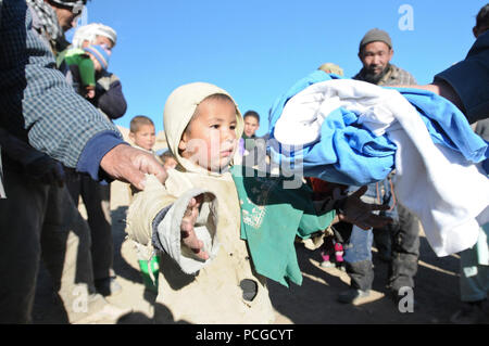 A young boy reaches for some warm clothes at Aq Robat, a remote village more than 20 miles northwest of Bamyan, Dec. 24. The clothes were donated by Operation Care: Afghanistan, a non-profit, private charitable organization based at Bagram Airfield, Afghanistan. Stock Photo