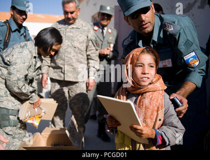 An Afghan girl receives school supplies from Afghan national policemen and coalition service members at an elementary school near Kandahar Air Field. During the visit, both Afghan and coalition leaders spoke to the children on the importance of education and good behavior before handing out school supplies. Stock Photo