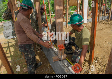 Armed Forces of the Philippines engineers, from the 552nd Engineer Construction Battalion, and U.S. Navy Seabees assigned to Naval Mobile Construction Battalion 5, discuss plans for construction at Don Joaquin Artuz Memorial Elementary School in Tapaz, Philippines, during Balikatan 2015, April 10. The engineers, along with U.S. Marines from the 9th Engineer Support Battalion, are part of the Combined-Joint Civil-Military Operations Task Force on the island of Panay and constructing two classrooms at the school. Balikatan, which means “shoulder to shoulder” in Filipino, is an annual bilateral t Stock Photo