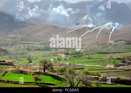 An AH-64 Apache helicopter shoots flares over a valley to support members of the 8th Commando Kandak and coalition special operations forces during a firefight near Nawa Garay village, Kajran district, Daykundi province, Afghanistan, April 3. Coalition SOF partners with the 8th Commando Kandak to conduct operations throughout Daykundi, Uruzgan and Zabul provinces. Stock Photo