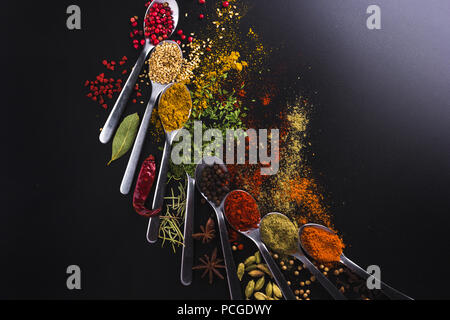 Composition of small spoons full of spices and condiments for cooking on a  black background Stock Photo - Alamy