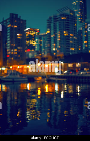 Blurred blurry soft focus background,  urban city life relax concept, lakeshore pier quay with boats, buildings, evening lights and reflections in wat Stock Photo