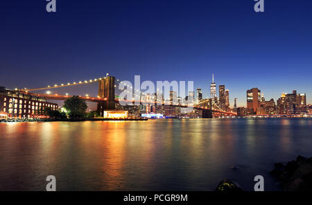 Panorama of Brooklyn Bridge and New York City (Lower Manhattan) with lights and reflections at dusk, USA Stock Photo