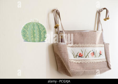 a beautiful handmade bag with a lovely embroidered pattern hung on the wall, used as a crafting bag. Stock Photo