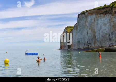 Saint-Pierre-en-Port (Normandy, northern France).  Cote d’Albatre (Alabaster coast). Chalk cliffs and swimmers on the pebble beach along the seaside.  Stock Photo