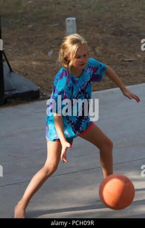 Pretty 8  year old female playing outdoor. basketball, wearing t-shirt and shorts. Model Relese #113 Stock Photo