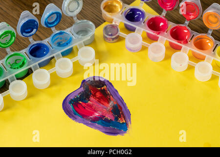 Palette mix watercolors. Children's watercolor paints. Colorful watercolor box.  Colorful heart on yellow paper. Stock Photo