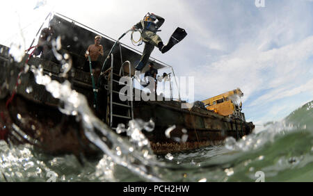 Petty Officer 2nd Class Jessie Trujillo, a Navy diver and a member of Mobile Diving and Salvage Unit 1, jumps off a barge for a surface supply dive supporting a Joint POW/MIA Accounting Command recovery mission. Stock Photo