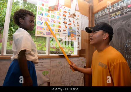 ARAWA, Autonomous Region of Bougainville, Papua New Guinea (June 29, 2015) Chief Ship’s Serviceman Eduardo Buenavente, attached to the Military Sealift Command hospital ship USNS Mercy (T-AH 19), recites the alphabet with a child from the Kobuan School during a Pacific Partnership 2015 community outreach event. Mercy is in Papua New Guinea for its second mission port of Pacific Partnership 2015. Pacific Partnership is in its 10th iteration and is the largest annual multilateral humanitarian assistance and disaster relief preparedness mission conducted in the Indo-Asia-Pacific region. Stock Photo