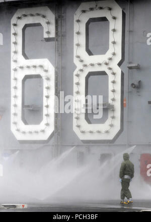 PACIFIC OCEAN (Nov. 15, 2012) A Sailor aboard the aircraft carrier USS Nimitz (CVN 68) takes part in a counter measure washdown on the flight deck. Nimitz successfully completed the ship's Joint Task Force Exercise (JTFEX), designed to test a strike group's ability to operate in hostile and complex environments with other U.S. and coalition forces. Stock Photo