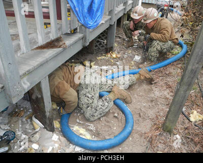 BREEZY POINT, N.Y. (Nov. 10, 2012) Construction Electrician 3rd Class Gayland Andrews, assigned to Naval Mobile Construction Battalion (NMCB) 5, adjusts suction hose while pumping water from a basement flooded during Hurricane Sandy. Stock Photo