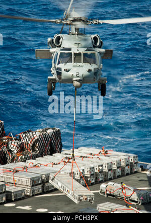 PACIFIC OCEAN (April 28, 2013) An MH-60S Sea Hawk helicopter assigned to the Indians of Helicopter Sea Combat Squadron (HSC) 6 lifts cargo from the Military Sealift Command dry cargo and ammunition ship USNS Richard E. Byrd (T-AKE 4) during a replenishment-at-sea with the aircraft carrier USS Nimitz (CVN 68). Nimitz and Carrier Air Wing 11 left San Diego for a western Pacific deployment. Stock Photo