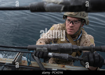 A U.S. Marine assigned to the 13th Marine Expeditionary Unit embarked aboard the amphibious assault ship USS Boxer (LHD 4) climbs aboard the guided missile destroyer USS Mason (DDG 87) during a visit, board, search and seizure exercise Jan. 12, 2014, in the Gulf of Oman. The Mason was deployed as part of the Harry S. Truman Carrier Strike Group in support of maritime security operations and theater security cooperation efforts in the U.S. 5th Fleet area of responsibility. Stock Photo