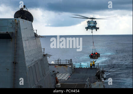 A U.S. Navy MH-60S Seahawk helicopter attached to Helicopter Sea Combat Squadron (HSC) 25 delivers supplies from the dry cargo and ammunition ship USNS Washington Chambers (T-AKE 11), not shown, to the guided-missile destroyer USS Mustin (DDG 89) during a replenishment at sea in the South China Sea Oct. 20, 2014. The Mustin was on patrol in the U.S. 7th Fleet area of responsibility supporting regional security and stability in the region. Stock Photo