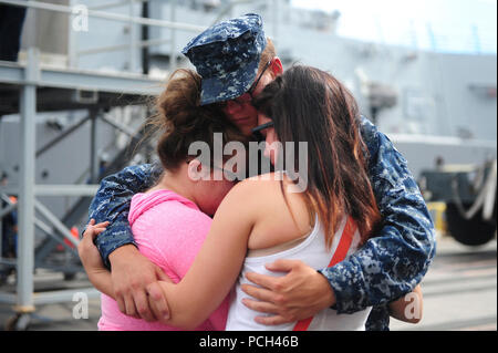 A U.S. Sailor assigned to the guided-missile destroyer USS Michael Murphy (DDG 112) embraces family and friends before leaving Joint Base Pearl Harbor-Hickam, Hawaii, for an independent deployment to the western Pacific Ocean Oct. 20, 2014. The Murphy was scheduled to conduct goodwill activities with partner nations along with various presence operations during the ship's first operational forward deployment. Stock Photo