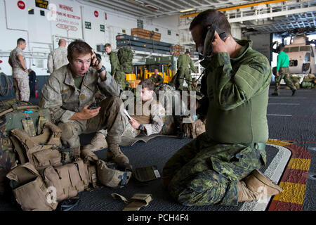 Royal New Zealand army Pvt. Jared Walch (left), assigned to the 1st Royal New Zealand Infantry Regiment (1RNZIR), and Cpl. Will Salikin, assigned to the 3rd Battalion Princess Patricia's Canadian Light Infantry (3PPCLI), test their portable radios in the hangar bay of the amphibious assault ship USS Peleliu (LHA 5) before a training exercise during Rim of the Pacific (RIMPAC) Exercise 2014. Twenty-two nations, 49 ships and six submarines, more than 200 aircraft and 25,000 personnel are participating in RIMPAC from June 26 to Aug. 1 in and around the Hawaiian Islands and Southern California. Th Stock Photo