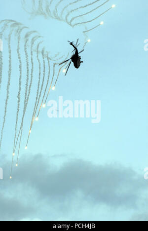 An HH-60H Seahawk assigned to the 'Black Knights' of Helicopter Anti-Submarine Squadron 4 displays the ability to launch flares and quickly maneuver out of a vulnerable position during an air power demonstration alongside the Nimitz-class aircraft carrier USS Ronald Reagan. The Ronald Reagan is on a scheduled deployment operating in the U.S. 3rd Fleet area of operation. Stock Photo