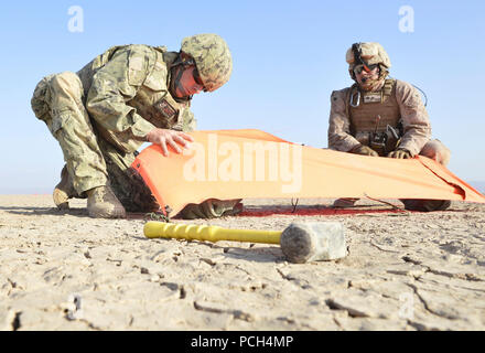 U.S. Navy Air-Traffic Controller 1st Class Derel Derryberry and U.S. Marine Corps Cpl. Vincent Depiazza set up a VS-17 signal marker panel while conducting aircraft landing zone training in support of Combined Joint Task Force- Horn of Africa, at Grand Bara, Djibouti, Jan. 28, 2017. The training, conducted with the Marine Air Traffic Control Mobile Team (MMT), allows Navy Air Traffic Controllers to gain experience, practice constructing an expeditionary airfield, and complete training and readiness requirements. Combined Joint Task Force-Horn of Africa is a multinational effort to conduct thea Stock Photo