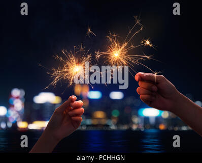 Couple holding a sparklers during nigh time city Stock Photo