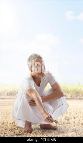 Farmer cutting dry grass in field Stock Photo