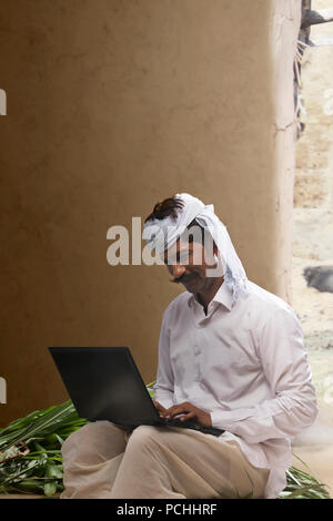 Indian farmer using laptop Stock Photo