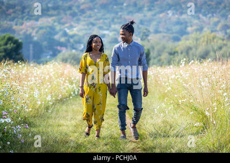 Couple holding hands walking in field Stock Photo