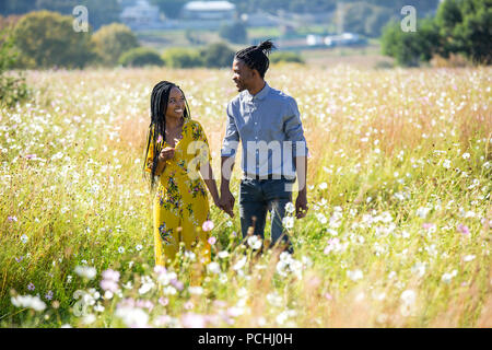 Couple holding hands walking in field Stock Photo