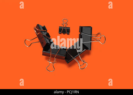 collection of paper clips on an orange surface Stock Photo