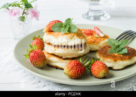 Curd pancakes with strawberries and mint on a plate Stock Photo