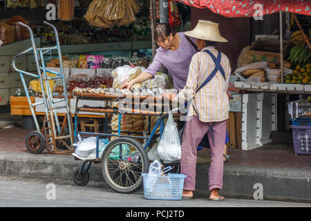 Bangkok, Thailand - 28th November 2014. Woman customer buying dried fish from a stree vendor in Chinatown, Vendors are everywhere in the city. Stock Photo