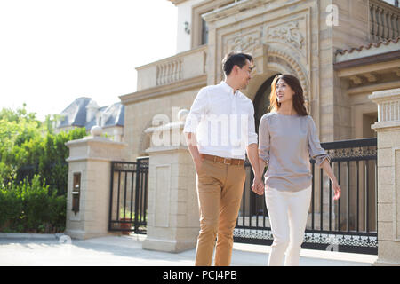 Cheerful young Chinese couple holding hands walking Stock Photo