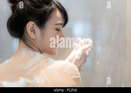 Young Asian woman taking a shower in the bathroom with Shower head. Looking happy and relax. Stock Photo