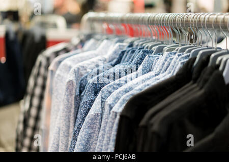 A row of colorful row t-shirts hanging on hangers in t-shirts retail shop. Stock Photo