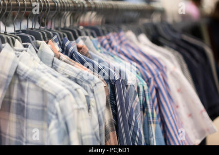 A row of colorful row t-shirts hanging on hangers in t-shirts retail shop. Stock Photo