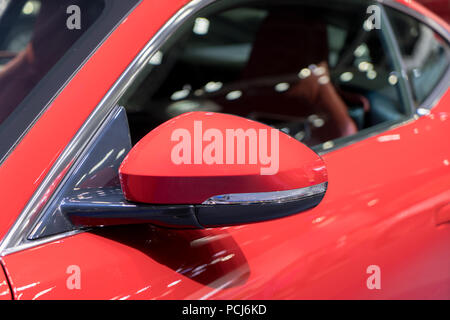 Red side view mirror with red sport modern car. Stock Photo