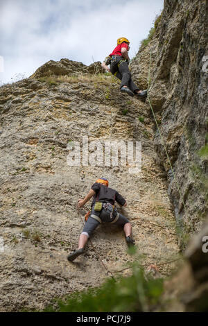 Photo from back of two climbing young sports guys in helmet on rock Stock Photo