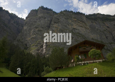 The spectacular upper Lauterbrunnen valley at Stechelberg: a chalet overlooked by sheer cliffs and a waterfall, Bernese Oberland, Switzerland Stock Photo